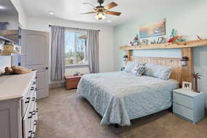 Carpeted bedroom featuring a ceiling fan, a baseboard radiator, and recessed lighting