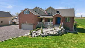 Craftsman house with an attached garage, gravel driveway, brick siding, board and batten siding, and a front lawn