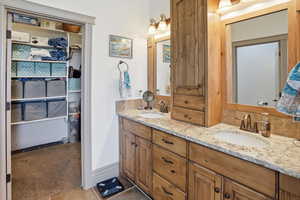 Bathroom featuring a spacious closet, double vanity, light carpet, and decorative backsplash