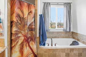 Full bath featuring a shower with shower curtain and a garden tub