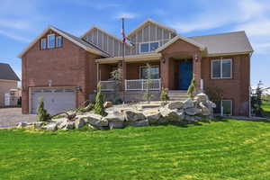 View of front of home with covered porch, a garage, a front yard, and brick siding