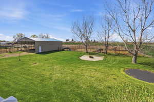View of yard with an outbuilding, a rural view, and a fire pit