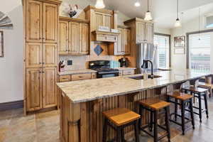 Kitchen featuring vaulted ceiling, black gas stove, light stone counters, tasteful backsplash, and pendant lighting