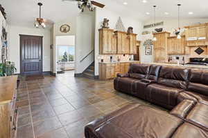 Living room with lofted ceiling, ceiling fan, and dark tile patterned flooring
