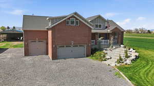 Back of house with gravel driveway, brick siding, a garage, and a porch