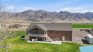 Rear view of property featuring a patio area, a yard, brick siding, and a mountain view
