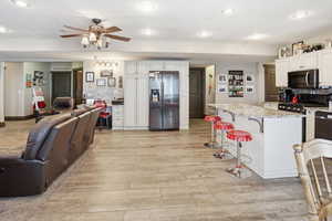 Kitchen featuring open floor plan, backsplash, stainless steel appliances, a breakfast bar, and a ceiling fan