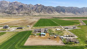Aerial view of property and surrounding area with rural landscape, rows of crops, and mountains