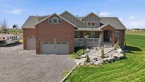View of front facade with covered porch, driveway, an attached garage, and brick siding
