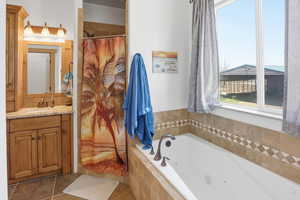 Bathroom featuring vanity, a shower with shower curtain, and a tub with jets