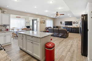 Kitchen with open floor plan, light stone countertops, freestanding refrigerator, light wood finished floors, and recessed lighting