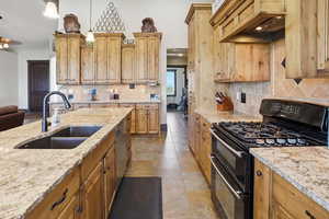 Kitchen featuring range with two ovens, light stone countertops, decorative backsplash, and pendant lighting
