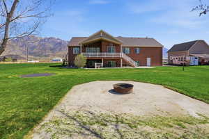 Back of property with a patio area, brick siding, an outdoor fire pit, a lawn, and a mountain view