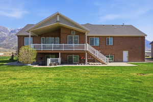 Back of property featuring a mountain view, brick siding, and a yard
