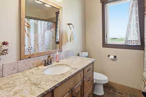 Full bath with curtained shower, vanity, and dark tile patterned flooring