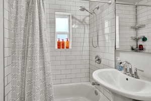 Bathroom featuring shower / bathtub combination with curtain and a sink