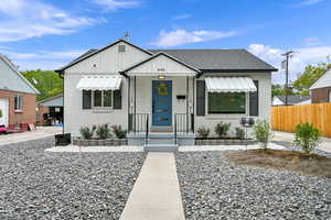 View of front of property with board and batten siding, brick siding, a porch, and a shingled roof