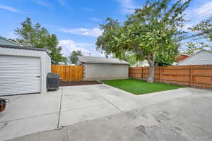 Fenced backyard featuring a grill, a patio area, and an outbuilding