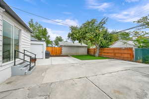 Fenced backyard with a grill, an outbuilding, and a patio