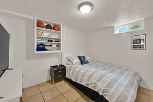 Bedroom with a textured ceiling and light tile patterned floors