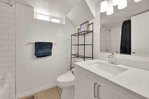Full bathroom with vanity, a textured ceiling, light tile patterned floors, and shower / bath combination with curtain