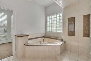 Full bath featuring light tile patterned flooring, a garden tub, light carpet, and tiled shower