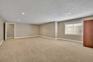 Unfurnished room with recessed lighting, light carpet, and a textured ceiling