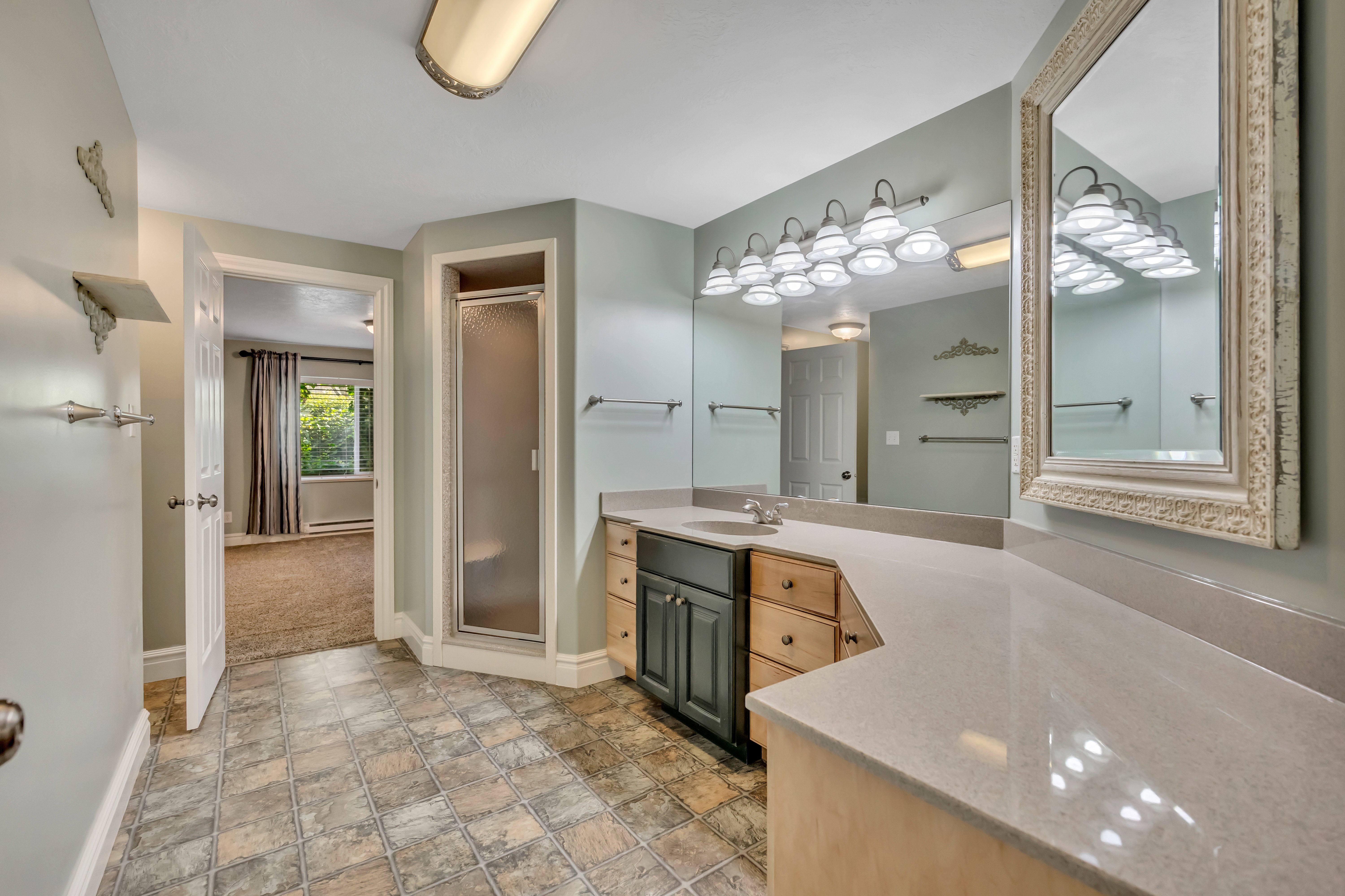 Bathroom with vanity, a stall shower, stone finish floors, and a baseboard heating unit