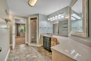 Bathroom with vanity, a stall shower, stone finish floors, and a baseboard heating unit