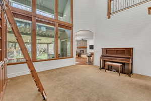 Sitting room featuring a high ceiling, light carpet, a fireplace, and arched walkways
