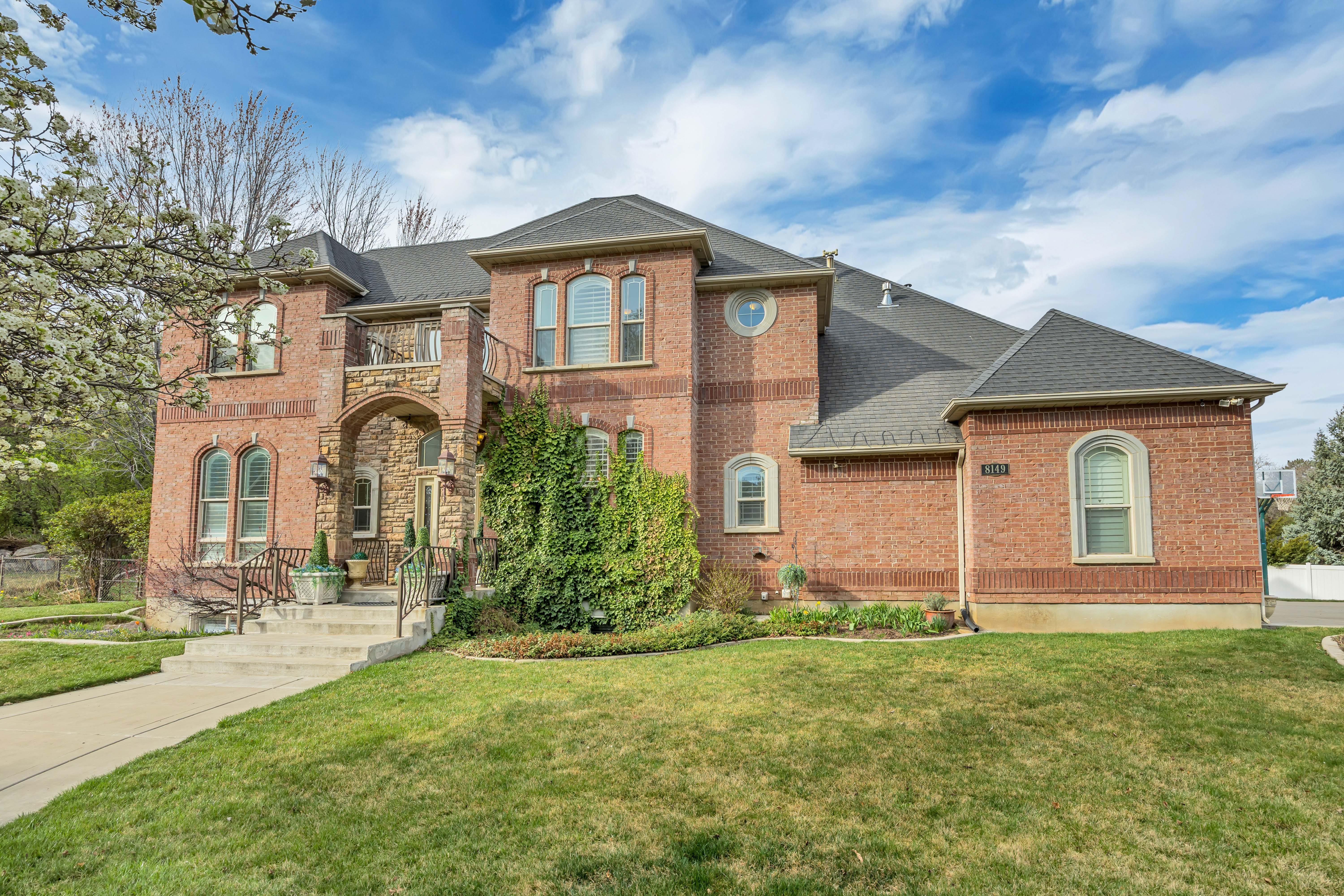 View of front of house with roof with shingles, brick siding, and a balcony