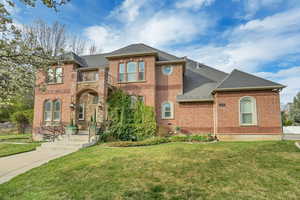 View of front of house with roof with shingles, brick siding, and a balcony
