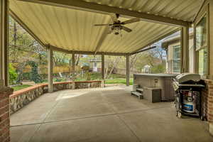 Fenced backyard featuring a patio area, grilling area, ceiling fan, a hot tub, and an outdoor structure