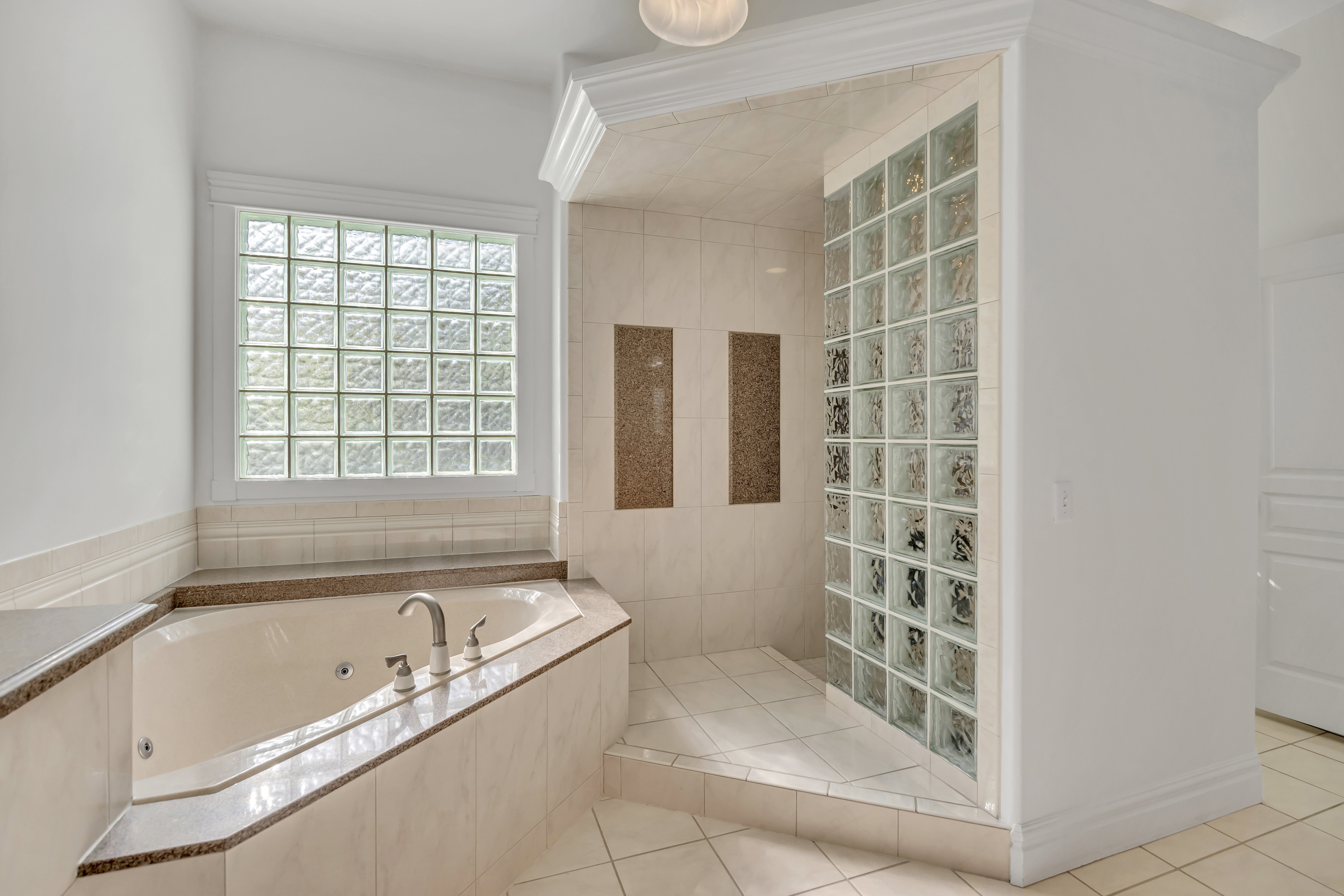 Bathroom with a walk in shower, light tile patterned floors, and a tub with jets