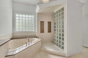 Bathroom with a walk in shower, light tile patterned floors, and a tub with jets