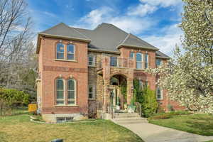 View of front of house with a front yard, brick siding, and roof with shingles