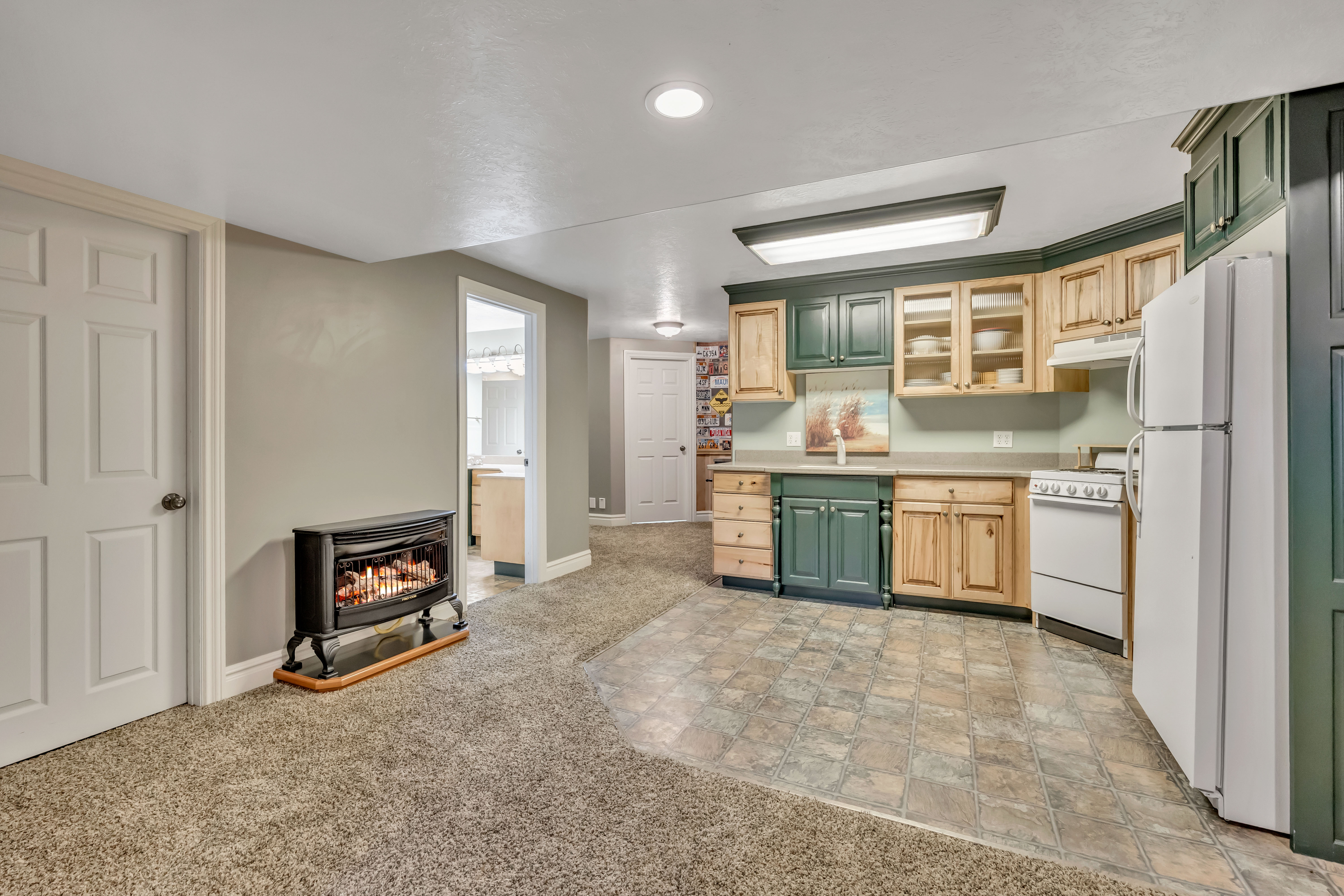 Kitchen featuring green cabinetry, white appliances, light countertops, glass insert cabinets, and light wood finish cabinetry