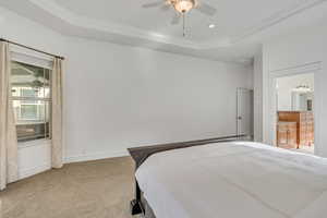 Bedroom with a tray ceiling, a ceiling fan, light colored carpet, ornamental molding, and recessed lighting
