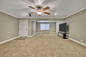 Unfurnished living room featuring ceiling fan, crown molding, light carpet, and a baseboard heating unit