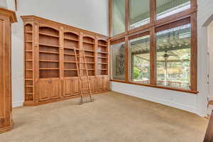 Unfurnished living room featuring a high ceiling and light colored carpet