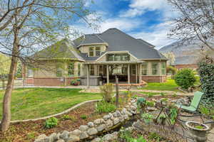 Rear view of property with a hot tub, a patio, brick siding, roof with shingles, and stucco siding