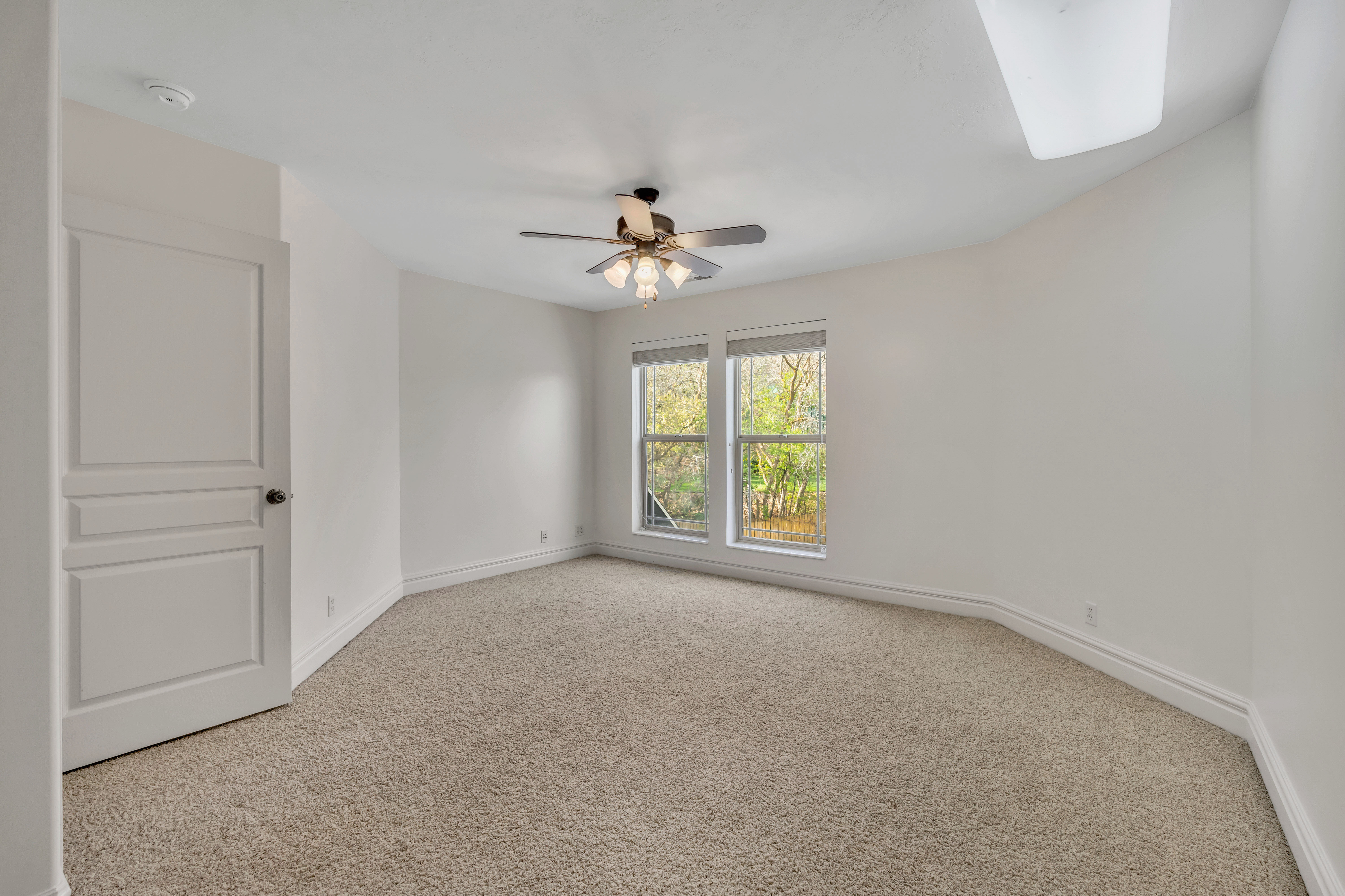 Empty room featuring light colored carpet and ceiling fan