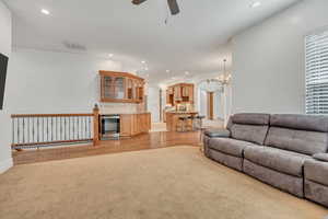 Living area with ceiling fan, light colored carpet, arched walkways, and suspended lighting