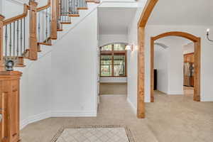 Entrance foyer featuring arched walkways, inlaid floor details, and light tile patterned floors