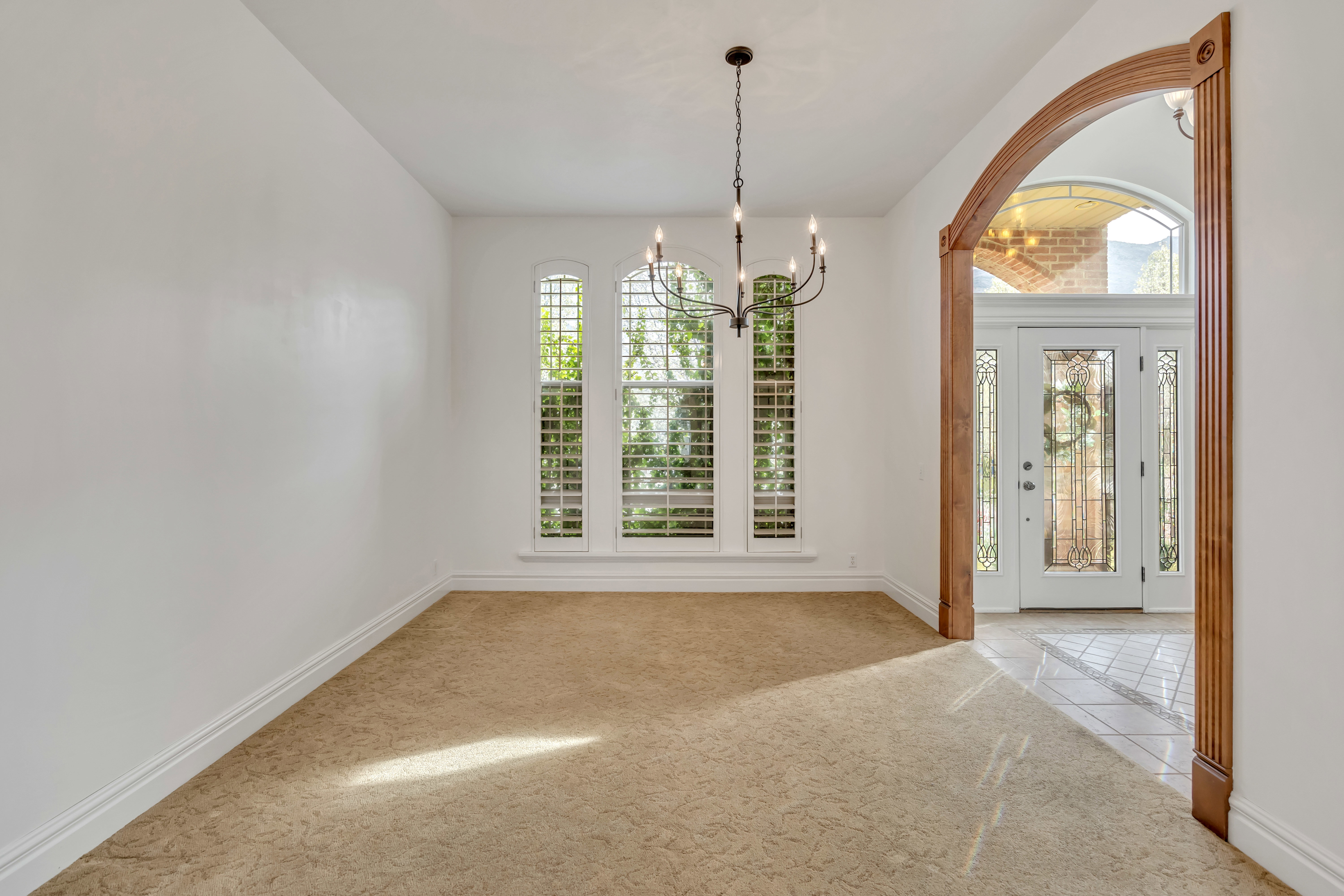 Foyer entrance with a chandelier, light colored carpet, and light tile patterned floors