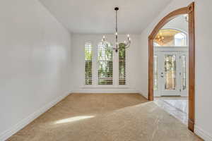 Foyer entrance with a chandelier, light colored carpet, and light tile patterned floors