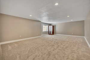 Empty room with light colored carpet, recessed lighting, and a textured ceiling