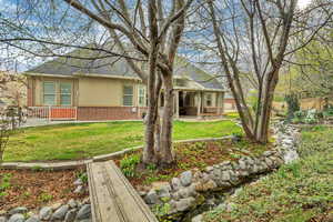 Back of property with brick siding, a patio area, a shingled roof, and stucco siding