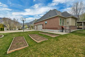 View of side of property with a gate, a garden, brick siding, a mountain view, and driveway