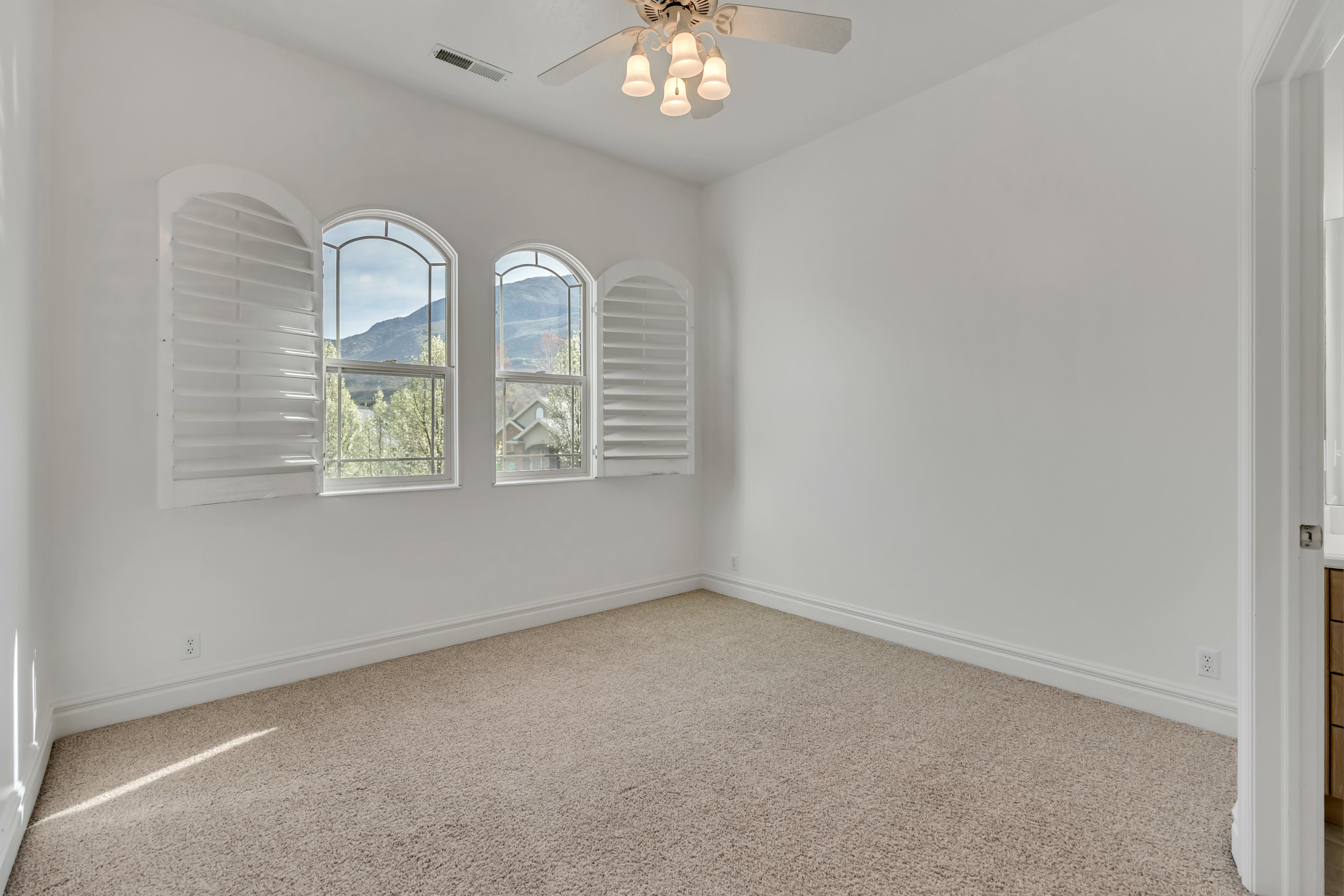 Unfurnished room with light carpet, ceiling fan, and a mountain view